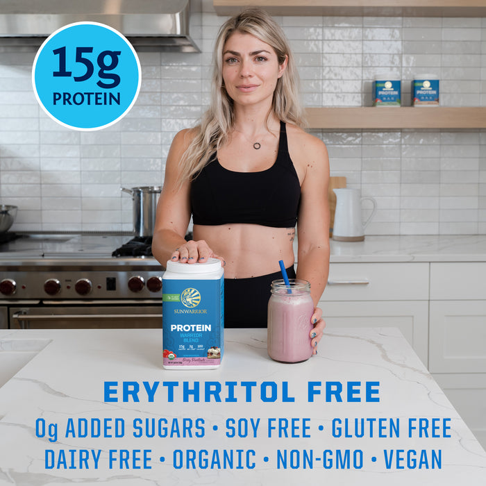 Woman in workout clothes holding a jar of pink protein shake and a container of plant-based protein powder on kitchen counter