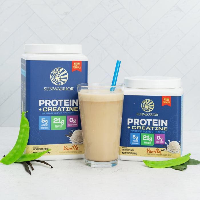 Two containers of vanilla plant-based protein powder and creatine by Sunwarrior with a vanilla smoothie in a glass and green leaves nearby