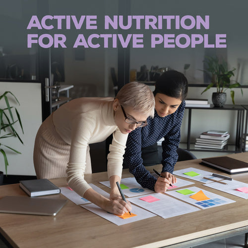 Two women collaborating over colorful charts and sticky notes on a table in a modern office with the text "Active Nutrition for Active People" above them.